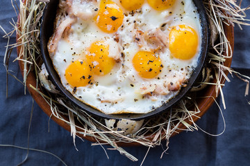 Fried eggs on a cast-iron frying pan. Scrambled eggs from quail eggs on a serving table. Close-up