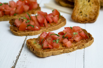 Tomato bruschetta food closeup. Bruschetta is a popular Italian appetizer (antipasto), made of crostini (grilled bread) and a topping of diced tomatoes, olive oil, herbs (basil) and garlic.
