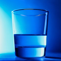 A glass of clean water close-up on a blue background isolated