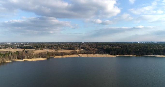 Lake bodom, Cinema 4k aerial flight towards yellow fields at bodom lake, on a sunny spring day, in Espoo, Finland