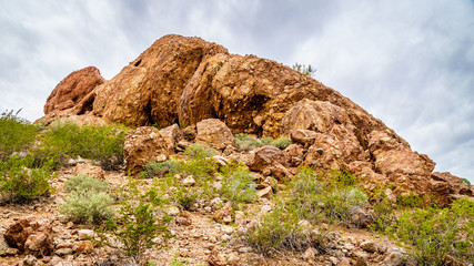 Fototapeta premium The red sandstone buttes of Papago Park, with its many caves and crevasses caused by erosion under cloudy sky, in the city of Tempe, Arizona in the United States of America