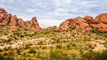Fototapeta premium The red sandstone buttes of Papago Park, with its many caves and crevasses caused by erosion under cloudy sky, in the city of Tempe, Arizona in the United States of America