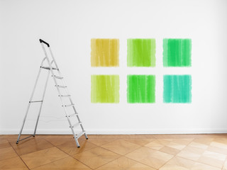 ladder in empty room, white wall with colored paint samples