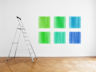 ladder in empty room, white wall with colored paint samples