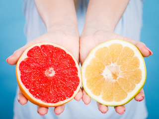 Halfs of yellow red grapefruit citrus fruit in human hands