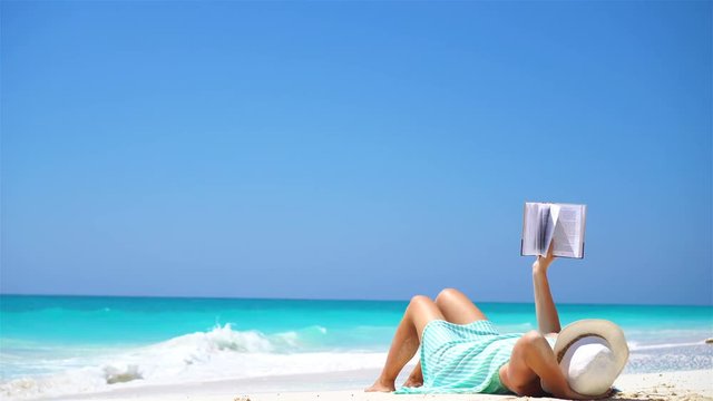 Young woman reading book during tropical white beach