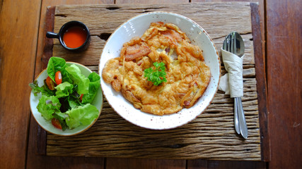 Omelet with salad greens, tomato, chill sauce and pair of fork and spoon