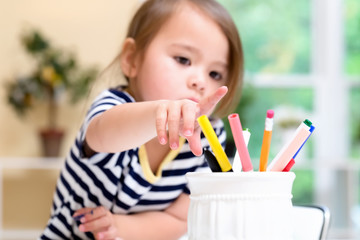 Toddler girl reaching for markers