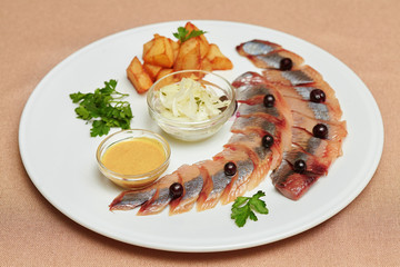 Pieces of herring with potatoes and greens on plate