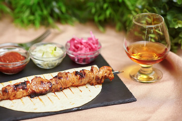 Shashlik kebab skewer on slate plate, sauce, onions and cognac