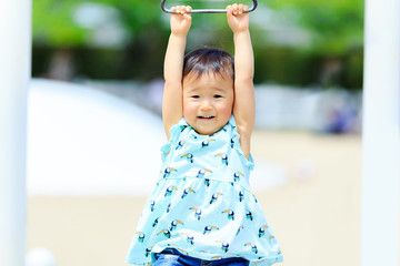 Fototapeta premium 公園の遊具にぶら下がっているかわいい子供