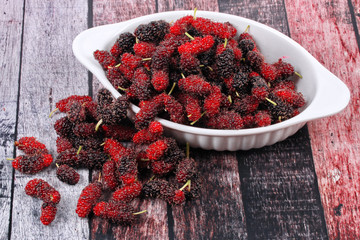 Fresh black and red ripe mulberries on wood