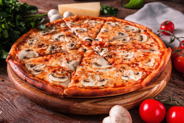 Appetizing italian food. Hot baked pizza with mushrooms and cheese served on wooden rustic table with ingredients.