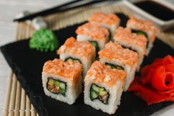 Appetizing set of sushi with cucumber, eel and avocado, served on black slate in luxury restaurant. Japanese uramaki, healthy food.