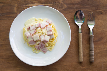 Spaghetti Carbonara with bacon in plate on wooden table.