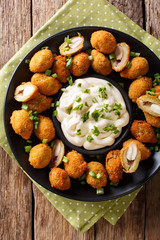 Appetizer of fried green olives with almonds close-up and sauce cream. Vertical top view