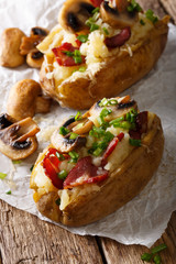 Baked potato stuffed with bacon, mushrooms and cheese close-up. vertical