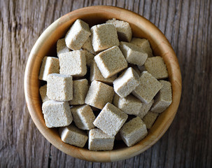 Sugar cubes in wood bowl on wood table