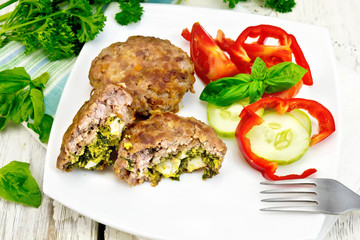 Cutlets stuffed with basil in plate on board