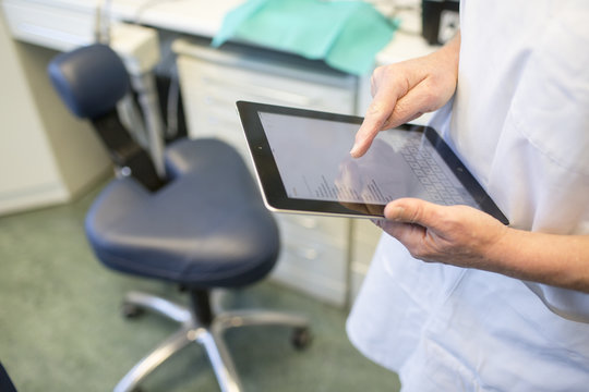 hands of a dentist working on a tablet computer