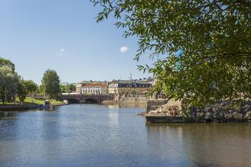 Naklejka premium Willow tree along a canal in Gothenburg with sunbathing people