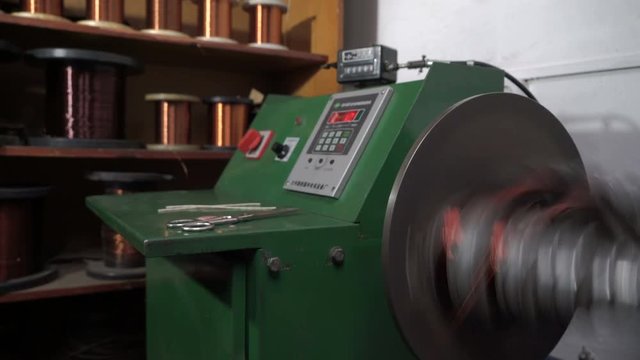 The worker winds the winding of the electric motor. The machine for winding. Electric motor repair