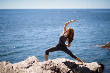 Young woman doing yoga in the beach