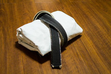 Black belt and Gi for martial arts ( Karate, Judo, Jiu-Jitsu, Kenpo, Taekwondo, Budo) on the wood...