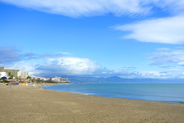 A beach of Costa del Sol before a tourist season, Mediterranean sea and a view to Torremolinos town, Andalusia, Spain.