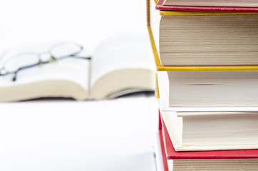 pile of books, high key still life with a pile of books and an open books in the background. culture. education. studying. reading.