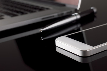 Close up Smartphone on table with laptop blur background. Technology and Business Concept