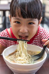 Asian little Chinese girl eating noodles soup
