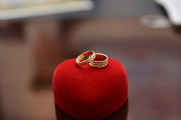 two wedding rings on a heart shaped red ring box