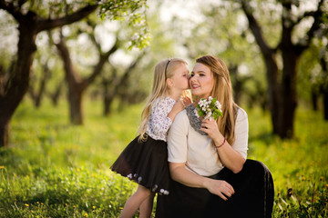 Obraz premium Little daughter gives her mother flowers for the holiday, a walk in the spring garden