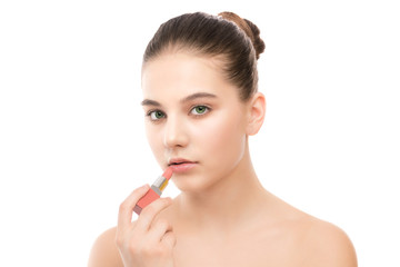 Portrait of beautiful young brunette woman with clean face. Beauty spa model girl with perfect fresh clean skin applying lipstick. Youth and skin care concept. Isolated on a white background.