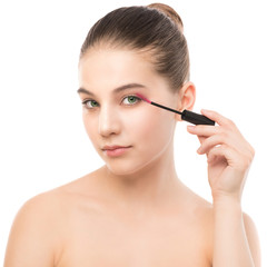 Fototapeta premium Eye make up apply. Mascara applying closeup, long lashes. Mascara brush. Portrait of beautiful young brunette woman with perfect fresh clean face skin. Eyelashes extensions. Make-up for green eyes