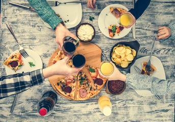 people clanging glasses together having pizza top view