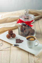 Chocolate balls truffles on a saucer next to a jar of candy and a Cup of coffee. The concept of delicious desserts gifts