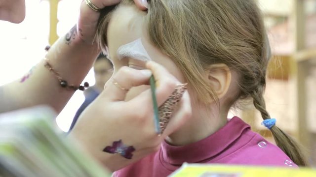 Child face painting like a cat