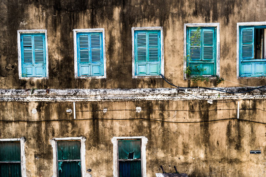 dirty neglected house with row of colorful windows in poor african region