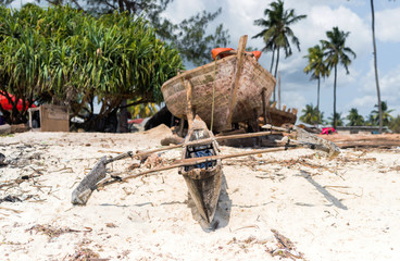 Fototapeta na wymiar old wooden fishing boat with paddles on a beach of fishing village in Zanzibar