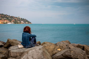 Femme sur la digue du port de Porto Santo Stefano en Toscane