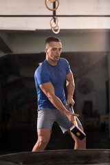 Fototapeta premium man workout with hammer and tractor tire