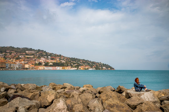 Femme sur la digue du port de Porto Santo Stefano en Toscane