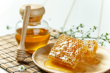 Sweet honeycomb and jar, white wooden background