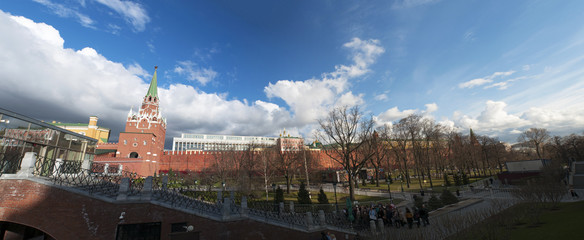 Mosca, 29/04/2017: panoramica del muro del Cremlino con la Torre Troitskaya (Torre della Trinità) e il ponte Troitsky che si affaccia sui Giardini di Alessandro, uno dei primi parchi urbani moscoviti - obrazy, fototapety, plakaty