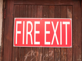 a big red and white sign outside on a fence saying fire exit wood metal