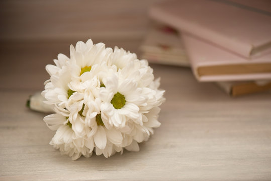 A white bouquet of flowers lies on a wooden table. Background or frame