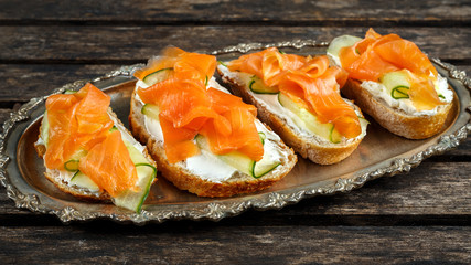 Smoked salmon bruschettas with soft cheese and cucumber shavings on a vitage plate