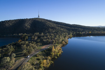 Fototapeta na wymiar Communications tower on top of hill by lake, blue sky